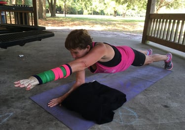 A woman with an arm cast performs a core-strengthening plank exercise on a yoga mat in a park.