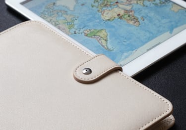 Close-up of a premium leather-bound business folder and a tablet showing a map of global trade routes. Professional, high-contrast photography with off-white and deep blue tones.