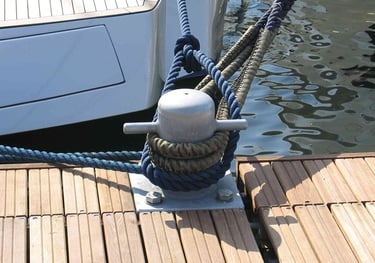 Cime di ormeggio nautiche blu fissate a un bitta di metallo accanto a una barca di lusso.