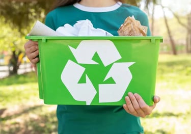 Una persona tiene in mano un bidone verde per la raccolta differenziata