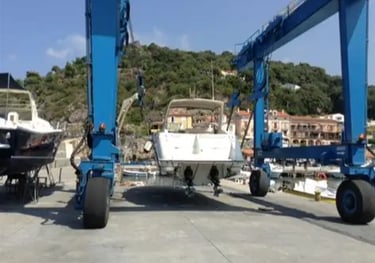 Un travel lift marino blu solleva dall'acqua un motoscafo per portarlo in servizio in cantiere