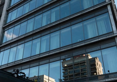 An architectural detail of a modern Brazilian law firm facade with glass windows reflecting a clear blue sky, evoking transparency and modernism.