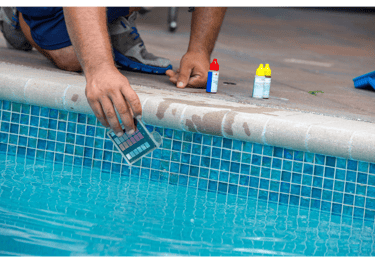 Image of a pool tech kneeling poolside performing a water test