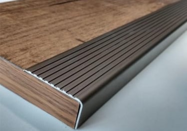foto zoom de uma cantoneira de aluminio sobre piso de madeira