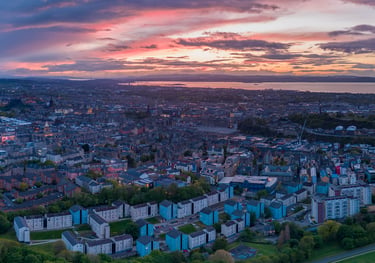 Aerial view of Edinburgh at dusk with dramatic pink sky over the city and Firth of Forth beyond