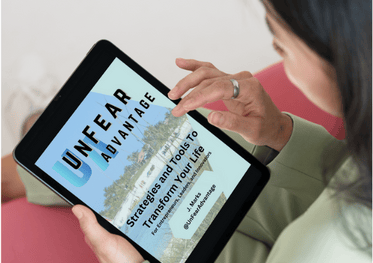 a woman holding a tablet computer and looking at a book called UnFear Advantage