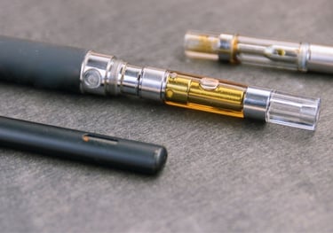 A collection of electronic vape pens and THC oil cartridges on a gray wooden surface.