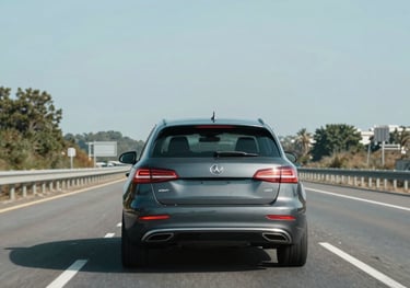 A flatbed truck carefully carrying a car on a sunny day.