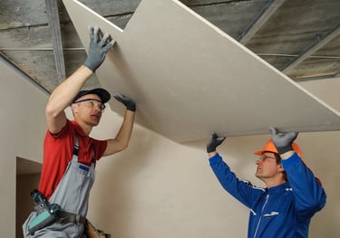 two men working on a ceiling with a ceiling fan