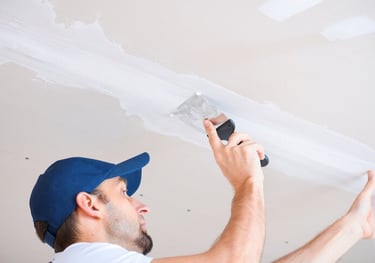 a man in a blue hat and a blue hat is texture matching and finishing a ceiling