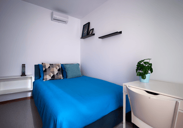 "Una cama azul y un escritorio blanco."