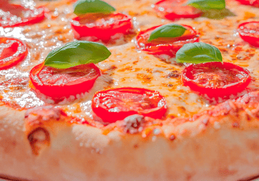 "Una pizza con tomates y albahaca por encima."
