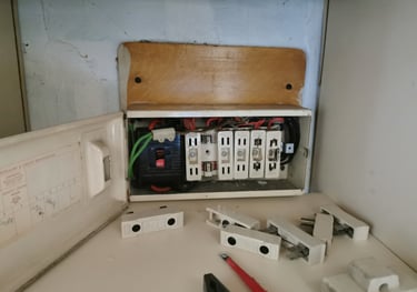 An old residential fuse box with ceramic wire fuses removed for electrical maintenance.
