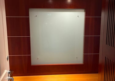 Modern office hallway featuring a frosted glass wall panel set in dark mahogany wood paneling with light oak floors.