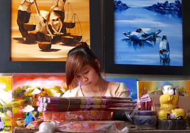 a woman sitting at a desk with a lot of art work