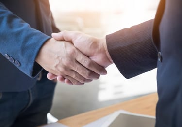 two people shaking hands with a laptop