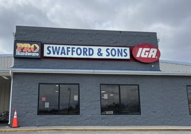 Exterior of Swafford and Sons IGA grocery store and Pro Hardware building with red and blue signs.