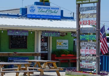 Exterior of The Veggie Wagon local island market with picnic tables and a signs for sandwiches and ice cream.