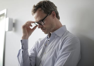 a man in a shirt and glasses is holding a cell phone