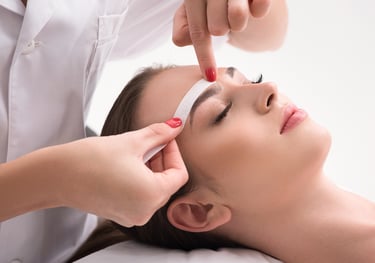 a woman getting a facial wax from a woman in a white shirt in a salon 