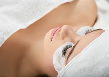 a woman with a white towel is having eyelash extensions applied to her lashes at a salon.