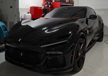A deep black Ferrari Purosangue after receiving a full front Paint Protection Film (PPF) installatio
