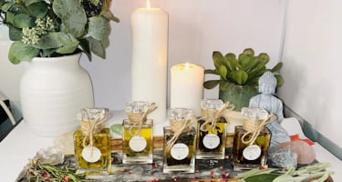 A serene arrangement featuring various essential oil bottles on a wooden tray surrounded by dried he