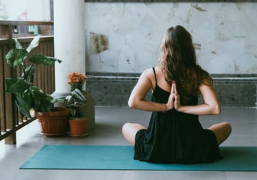 woman wearing black shirt sitting on green yoga mat