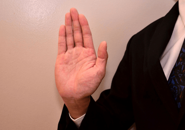 a man in a suit and tie is holding his hand up to the camera