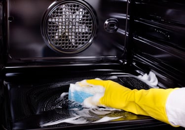 avra cleaning services person cleaning a stove top oven with a sponge pad