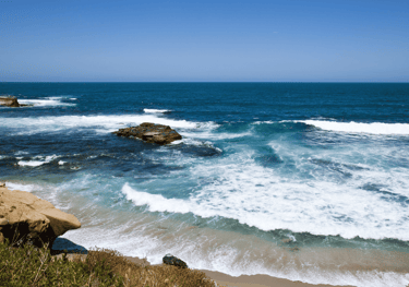 a view of a beach with waves crashing over the rocks