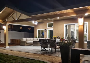 Alumawood patio cover with lighting and patio furniture taken at night.ht