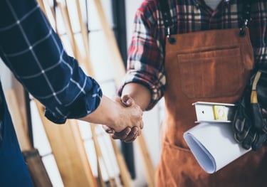 Männer in Arbeitskleidung, die sich freundlich die Hand reichen