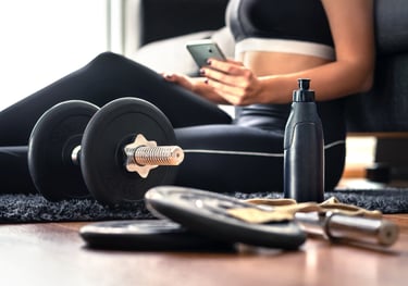 Online personal training at home—woman on lounge room floor with dumbbells and plan, virtual coachin