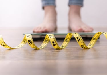 Sustainable fat-loss coaching—person stepping on scales with tape measure, weekly check-ins 