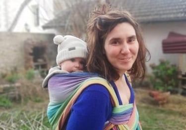 femme portant son bébé en écharpe sur le dos