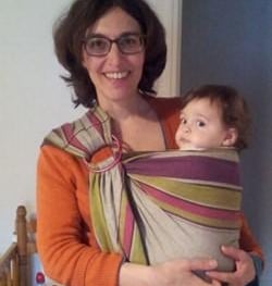 femme souriante portant son bébé en écharpe de coté