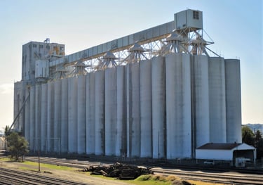 a large grain silo with a train passing by