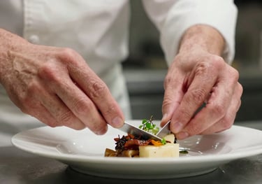 A detailed close-up of a chef's hands carefully plating a dish in a Michelin-star style kitchen. The focus is on precision and quality, representing professional integrity.