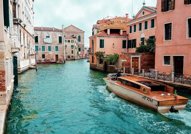 Um táxi aquático de madeira percorre um canal turquesa em Veneza, Itália, cercado por edifícios hist