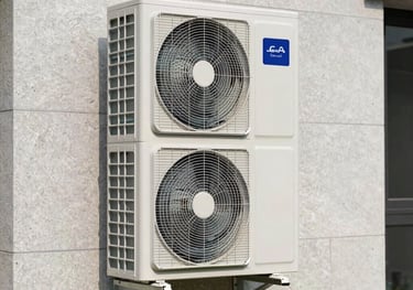 Outdoor unit of a high-end white air-to-water heat pump installed against a light grey stone wall of a modern villa. Professional photography, clean installation.