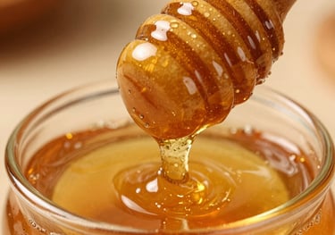 Macro shot of liquid gold honey being drizzled from a wooden dipper. The texture is thick and translucent with a rich amber hue.