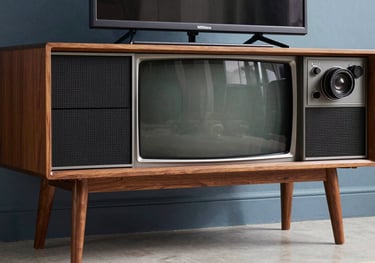 A close-up of a designer television from 1978 with a sleek wooden frame and tapered legs, set against a muted slate blue wall, European / French interior, photography.