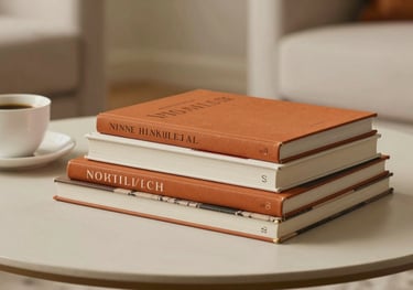 A lifestyle photography shot of several art books stacked on a low coffee table, a cup of coffee nearby, soft off-white and burnt orange tones, European / French home, photography.