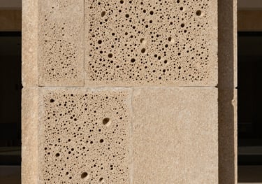 Detailed shot of a beige cantera stone wall, showcasing the porous texture and traditional Mexican hand-carved finishing in a modern architectural context.