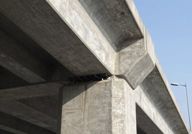 Low angle view of a reinforced concrete highway bridge structure with support pillars and beams.