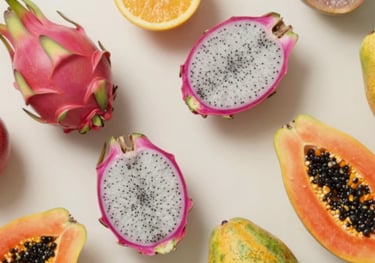 A top-down, artistic arrangement of diverse exotic fruits like dragonfruit and papaya on a clean, light surface. The lighting is natural and bright, highlighting the vibrant textures against the #EBF3EE background.