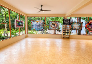 Spacious art gallery with psychedelic tapestries and panoramic windows overlooking a lush tropical forest.