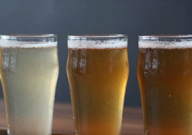 Close up of a beer flight with three different colors of beer in small glasses, mist grey and dark slate industrial background.