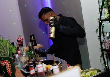Professional mixologist in black uniform using a gold cocktail shaker at a private event bar.